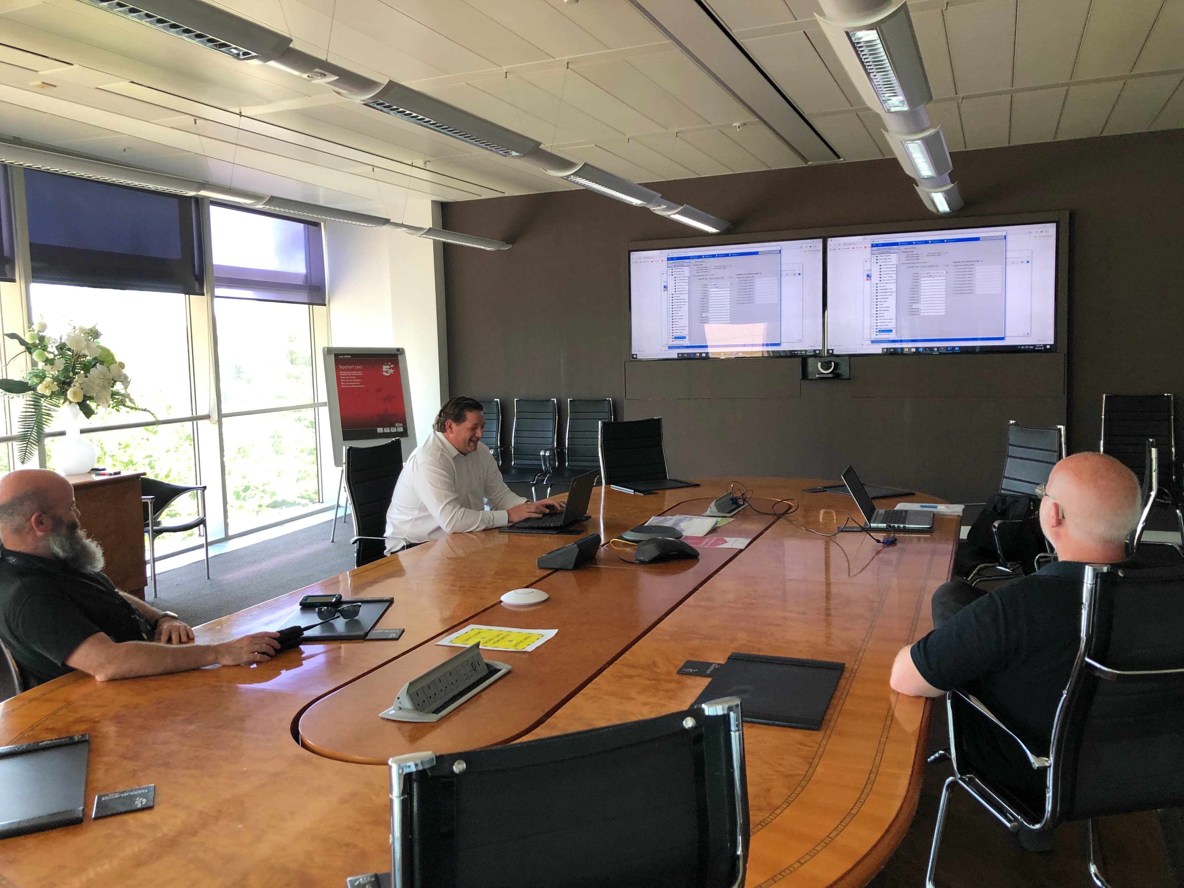 3 people round a conference table viewing analytics